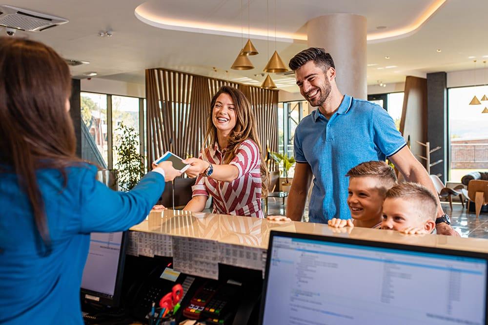 Smiling family of four in the hotel lobby check in