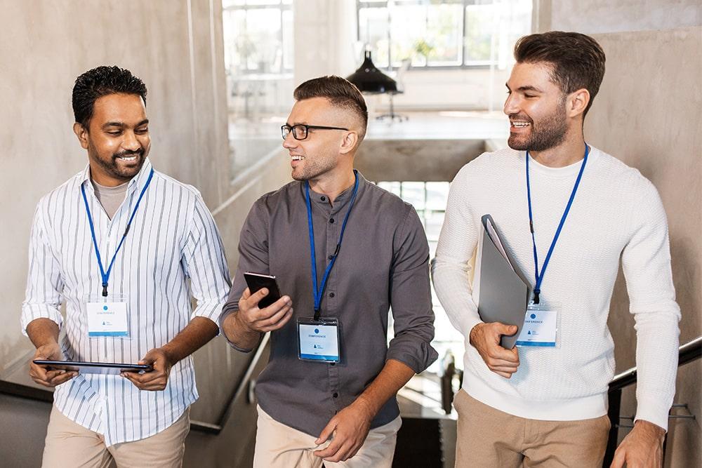 group of hotel conference attendees wearing badges and carrying phones, laptops, and tablets